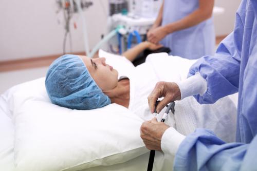 A female patient lying on a bed in a hospital operating theatre with nurses - Australian Stock Image