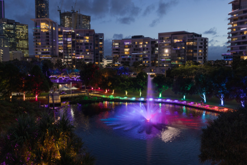 A fountain is lit up at night during an event at the Roma Street Parklands in Brisbane city - Australian Stock Image