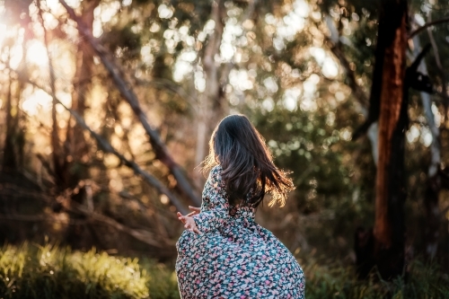 a girl twirling at the park in sunset - Australian Stock Image