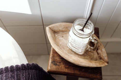 A glass jar with a powder and spoon on a wooden tray. - Australian Stock Image