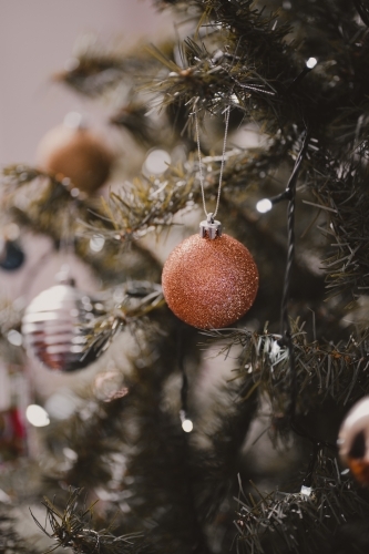 A gold glitter bauble decoration on a Christmas tree - Australian Stock Image