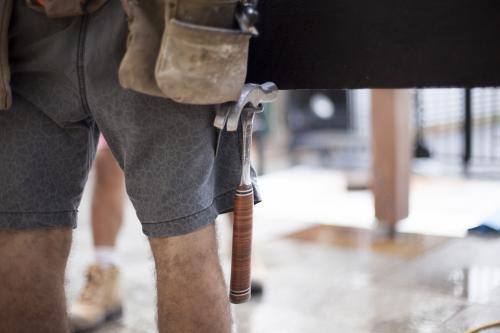 A hammer sits in a tradesman's belt. - Australian Stock Image