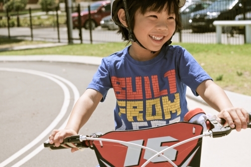 a kid happily riding his bike at the park - Australian Stock Image