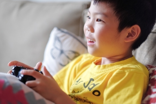 a kid, playing a console game in the living room