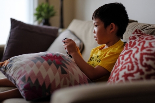 a kid, playing a console game in the living room