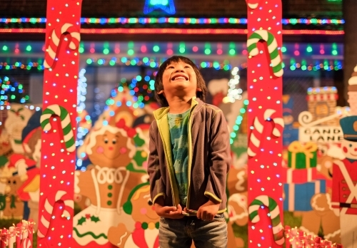 a kid, smiling and dazzled by the Christmas lights and decorations - Australian Stock Image