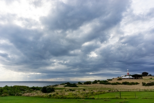 A light house in a coastal rural area with cloudy sky at Low Head - Australian Stock Image