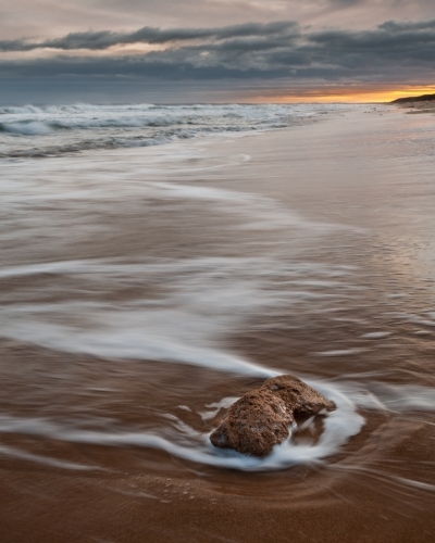 A Lone Rock Being Hit by the Incoming Tide at Thirteenth Beach, Sunrise - Australian Stock Image