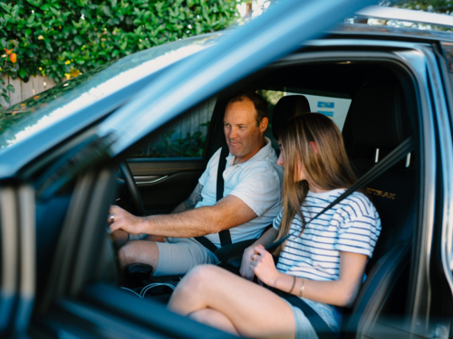 A man and young teenage girl sitting inside the car. - Australian Stock Image