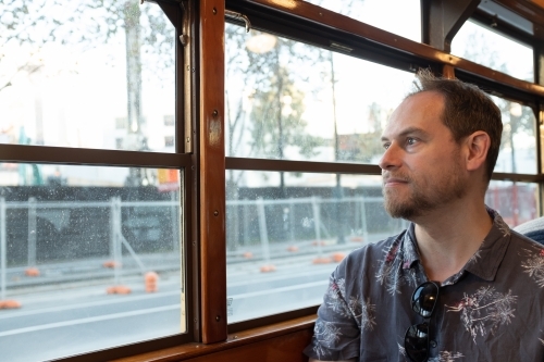 A man sitting in a famous historic Melbourne W Class tram looking out the window - Australian Stock Image