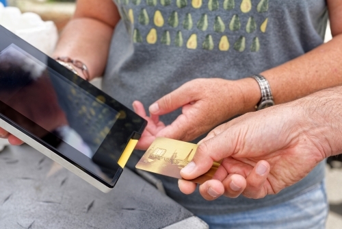 A man using technology making a mobile eftpos payment with a credit card - Australian Stock Image