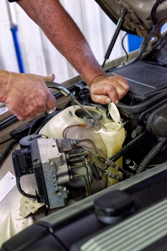 A mechanic servicing a luxury car in his workshop on the Gold Coast - Australian Stock Image