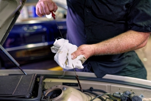 A mechanic servicing a luxury car in his workshop on the Gold Coast - Australian Stock Image