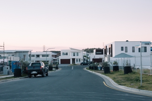 A newly developed suburban street with modern homes, parked cars on street at dusk - Australian Stock Image