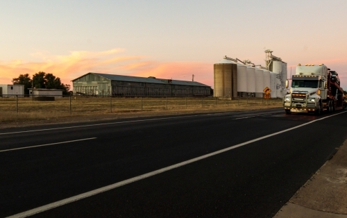 A semitrailer driving past grain silos with pretty sunset in the background - Australian Stock Image