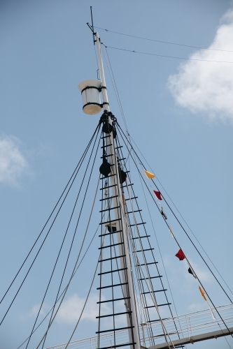 A ship's mast with signal flags at the top and lines of ropes. - Australian Stock Image