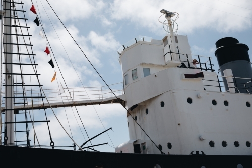 A ship's mast with signal flags at the top and rope lines - Australian Stock Image