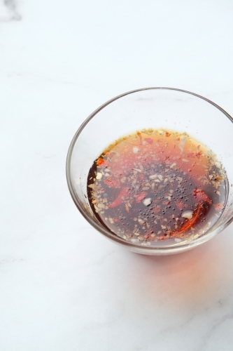 a small glass bowl with dark red sauce and spices - Australian Stock Image