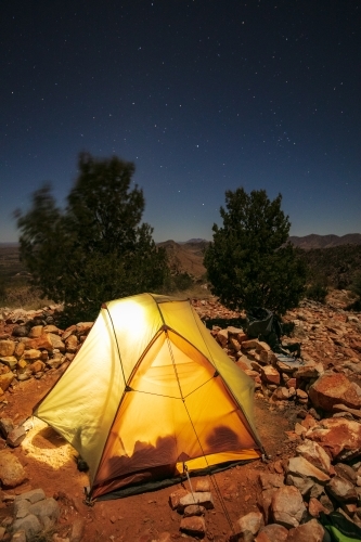 A small two man tent glows in the night as it is illuminated from inside. - Australian Stock Image