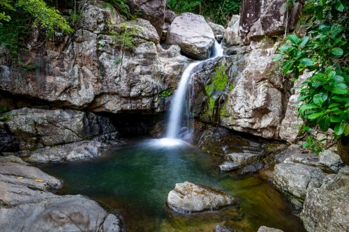 A small waterfall surrounded by large smooth rocks - Australian Stock Image