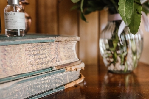 A stack of old books with worn edges on a wooden table. - Australian Stock Image