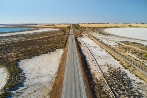 A straight section of bitumen road through dry salt lakes near Wongan Hills, Western Australia. - Australian Stock Image