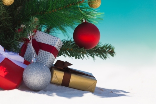 A summery Christmas. A closeup of a Christmas tree decorated with baubles and with wrapped gifts - Australian Stock Image