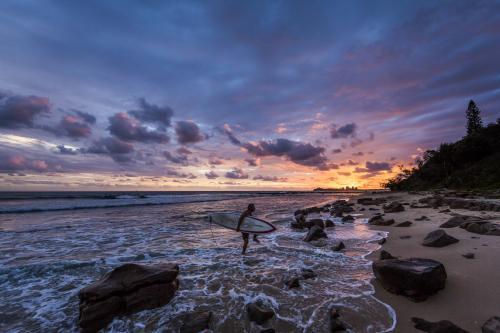 A surfer exiting the water at sunrise