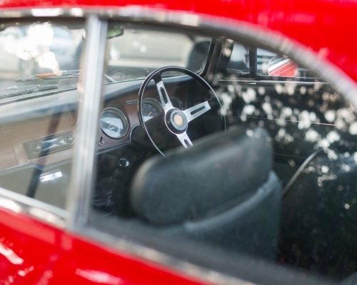 A three spoke steering wheel inside a shiny red car - Australian Stock Image