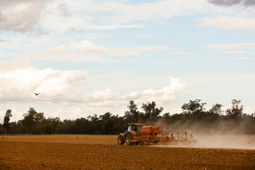 A tractor and seeder dry sowing a crop under a cloudy sky - Australian Stock Image