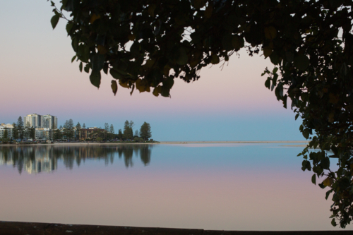 A tranquil waterfront cityscape at twilight, with pastel sky and a reflection of buildings - Australian Stock Image