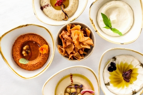 A variety of hummus dips arranged on a white countertop. - Australian Stock Image