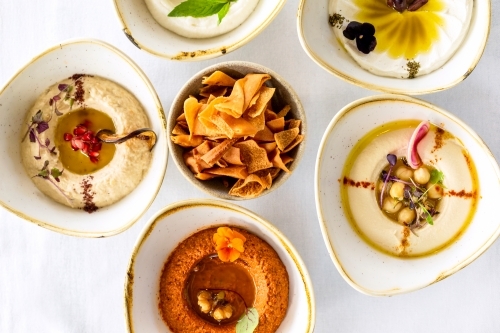 A variety of hummus dips arranged on a white countertop. - Australian Stock Image