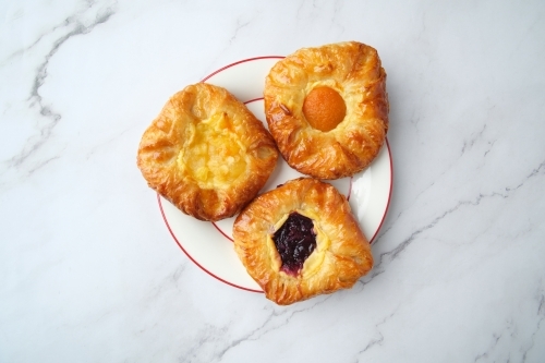 A variety of pastries on a plate with red circular rim. - Australian Stock Image