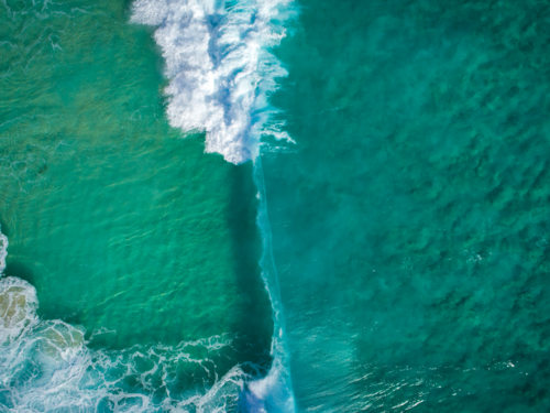 A wall of water is moments away from collapsing over crystal clear water - Australian Stock Image