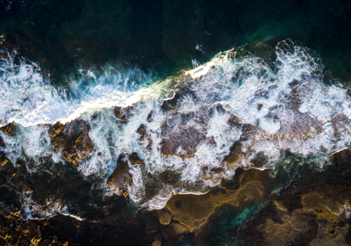 A wave crashed over an eposed reef after dawn - Australian Stock Image