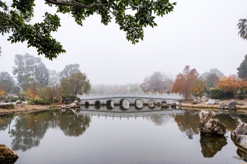 A white, multi-arched bridge crossing over a calm water. - Australian Stock Image