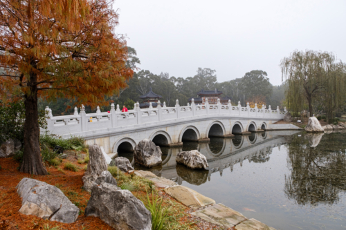 A white, multi-arched bridge crossing over a calm water. - Australian Stock Image