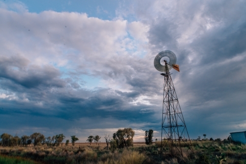 A windmill standing tall against the dark cloudy sky. - Australian Stock Image