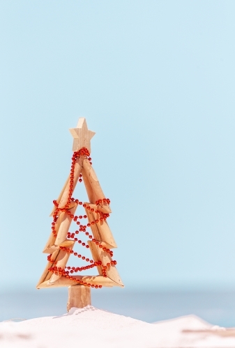 A wooden Christmas tree decorated with red baubles stands on the beach in Australia - Australian Stock Image