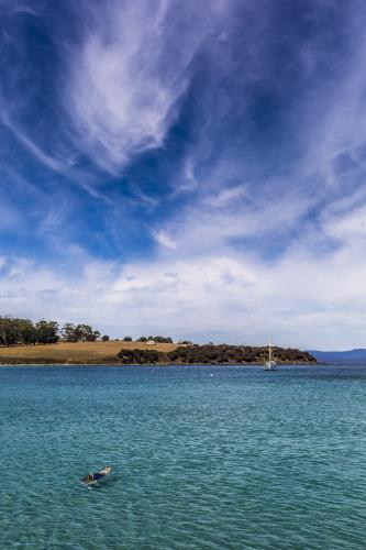 A yacht and snorkeler in the clear water around Maria Island. - Australian Stock Image