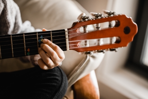 A young caucasion girl practicing playing her guitar