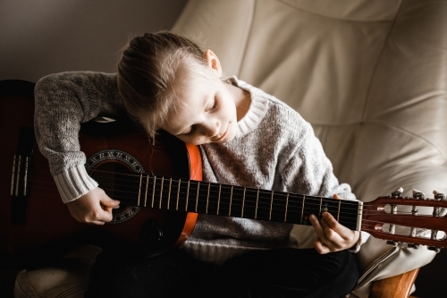 A young caucasion girl practicing playing her guitar - Australian Stock Image