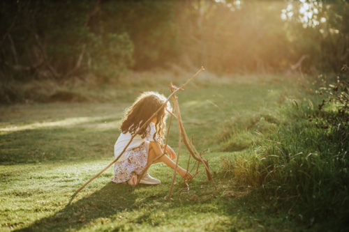 A young girl playing at the park with sticks - Australian Stock Image