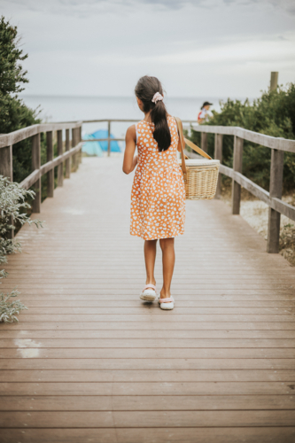 A young girl walking to the beach carrying a picnic basket - Australian Stock Image