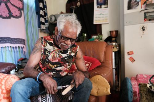 Aboriginal Artist Making a Message Stick using Wood Burner - Australian Stock Image