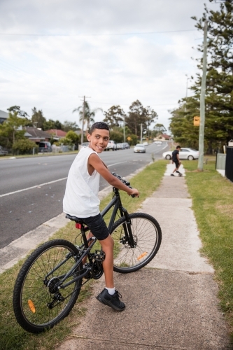 Aboriginal boy riding bike on footpath