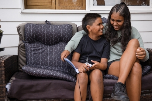 Aboriginal girl and young Aboriginal boy sitting together - Australian Stock Image