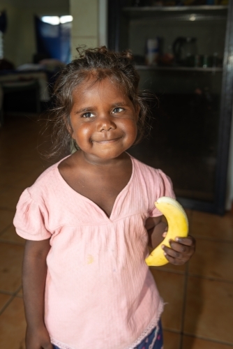 Aboriginal girl eating banana - Australian Stock Image