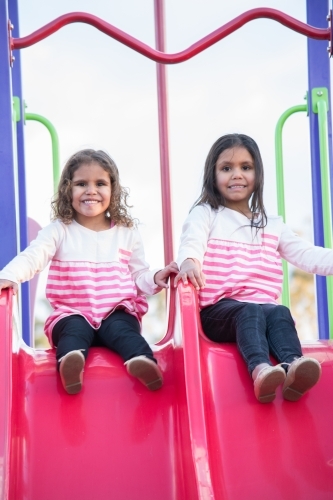 Aboriginal girls on slide at park - Australian Stock Image